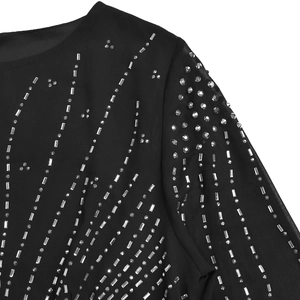 Detail of elegant black sheer dress featuring silver sequins and sparkling rhinestones