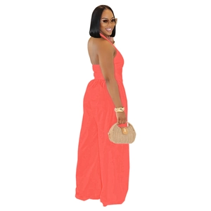 Detail view of coral orange backless halter jumpsuit with wide legs and lightweight fabric