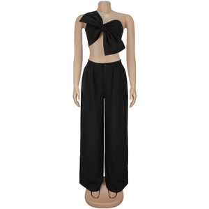 Detail of a black two-piece set featuring a one-shoulder bow top and high-waist trousers