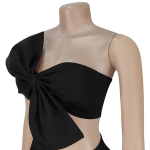 Detail of black one-shoulder cropped top featuring a large decorative bow on shoulder