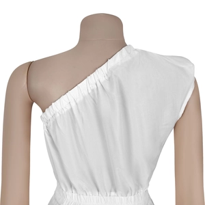 Gros plan sur la robe blanche asymétrique avec décolleté smocké et texture en coton lin