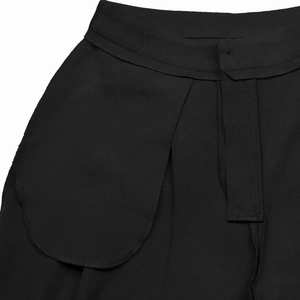 Detail shot of the high-waisted black pants showing pocket flaps and refined stitching