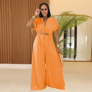 Detail of vibrant orange v-neck jumpsuit featuring waist cut-outs and drawstring ties