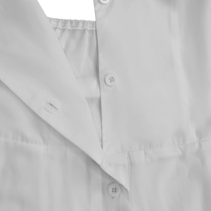 Détail de la texture du tissu blanc avec boutons ronds et encolure plissée élastique