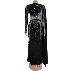 Détail d'une robe moulante noire avec des strass brillants et une cape en tulle fin