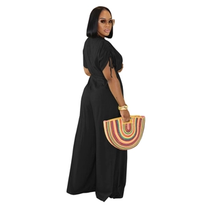 Detail of black pleated V-neck jumpsuit with wide-leg trousers and matching waist tie belt