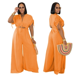 Detail of bright orange V-neck jumpsuit with waist cut-outs and wide-leg trousers