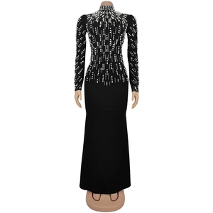 Detail of elegant black long-sleeve dress featuring vertical white pearl bead decorations