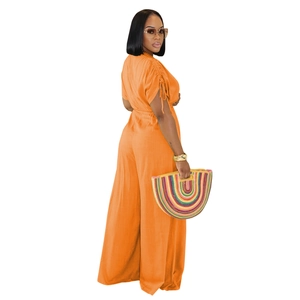 Detail of vibrant orange v-neck jumpsuit featuring drawstring cuffs and rainbow woven bag