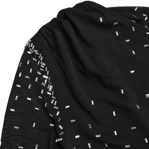 Détail d'une robe de soirée noire avec manches en maille transparente et strass argentés