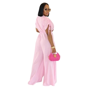 Detail of pink V-neck jumpsuit showing ruffled sleeves and textured fabric waist tie