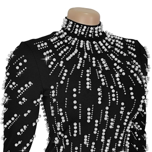Detail of black turtleneck dress featuring radial faux pearl beading and rhinestone accents