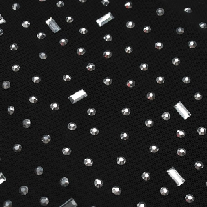 Macro detail of sparkling rhinestones on black mesh fabric for a sexy slit evening dress