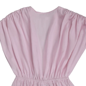 Detail of light pink V-neck jumpsuit featuring elegant pleated fabric and gathered waist