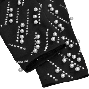 Detailed view of white pearls and silver rhinestones on black long sleeve dress fabric