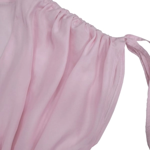 Detail of light pink jumpsuit with pleated V-neckline and delicate fabric texture