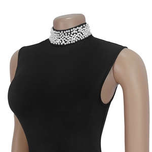 Close-up of elegant pearl embellishments on a black sleeveless turtleneck slim dress