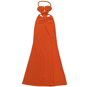 Detail of orange knitted halter dress featuring woven flower accent and high side slit