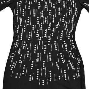 Detailed view of black dress featuring elegant white pearls and sparkling rhinestone stripes