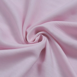 Close-up of light pink fabric texture with elegant spiral draping and silky smooth finish