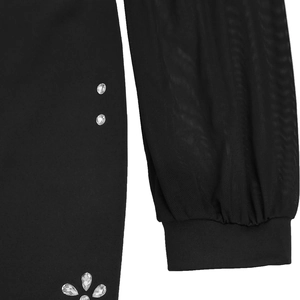 Dettaglio delle maniche in rete nera e dei motivi floreali di strass sull'abito elegante