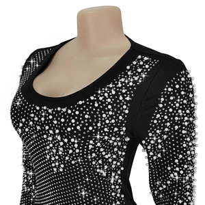 Close-up detail of white pearls and sparkling rhinestones on black long sleeve dress