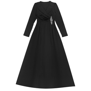Dettaglio dell'elegante abito a portafoglio nero con una spilla di cristallo lucente in vita