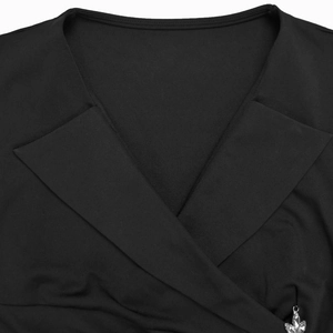 Dettaglio dell'abito a portafoglio con scollo a V e ciondolo di cristallo su maglia nera