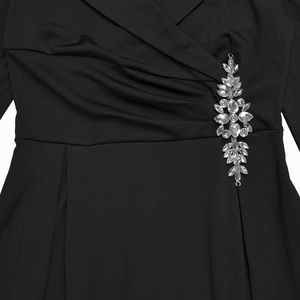 Dettaglio dello scollo a V con drappeggio e lussuoso ornamento a foglia di strass in vita