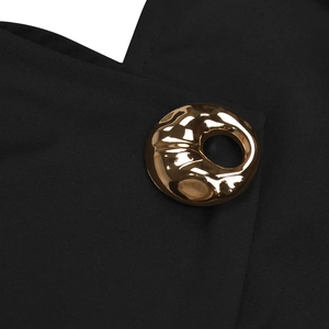 Close-up of elegant gold irregular metal buckle on minimalist black sleeveless outfit