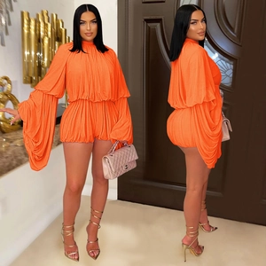 Detailed close-up of vibrant orange pleated romper with layered ruffle lantern sleeves