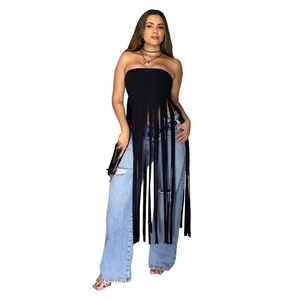 Dettaglio di un top a fascia nero con frange abbinato a jeans in denim blu chiaro strappati