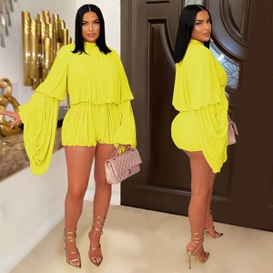 Detail of bright yellow pleated playsuit with high neck and voluminous puff sleeves