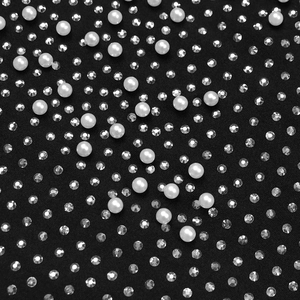 Detail of elegant black dress fabric with white faux pearls and shiny rhinestones