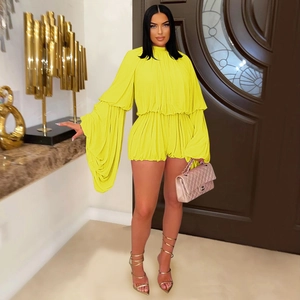 Detail view of bright yellow pleated two-piece set featuring dramatic bell sleeves and shorts