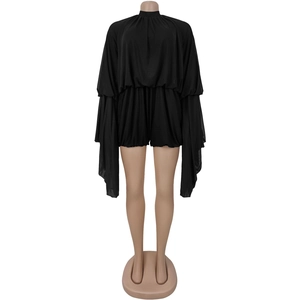 Detail of black long sleeve romper featuring wide cape sleeves and pleated texture