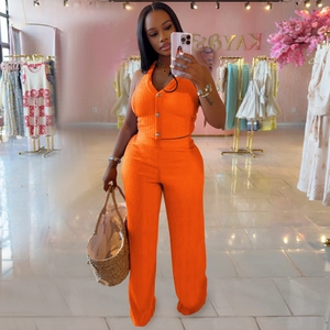 Detail of orange ribbed knit set featuring a halter button vest and wide-leg trousers