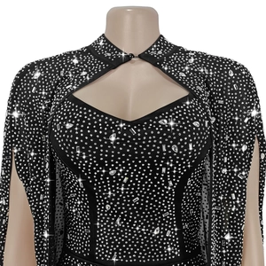 Détail de robe moulante noire avec strass, col évidé et manches cape élégantes
