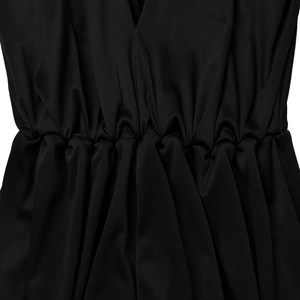 Detail view of the elastic pleated waist and deep V-neckline on a black jumpsuit fabric