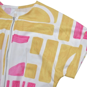 Detail of round neckline and metal zipper closure on colorful geometric print jumpsuit