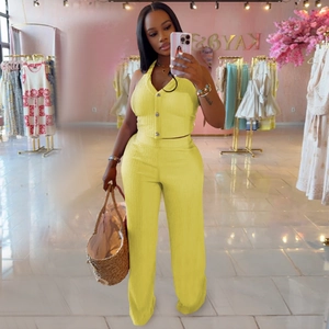 Detail view of yellow halter button top and high-waist wide-leg trousers with ribbed texture
