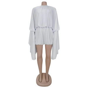 Detail of light grey pleated romper featuring dramatic split long sleeves and high neckline