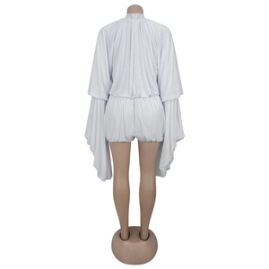 Detailed back view of white pleated romper featuring dramatic batwing sleeves and high collar
