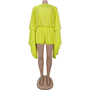 Detail of neon yellow romper featuring dramatic long cape sleeves and pleated waist design