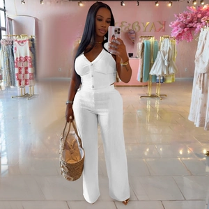 Detail of white two-piece set featuring V-neck buttoned vest and high-waist wide-leg trousers