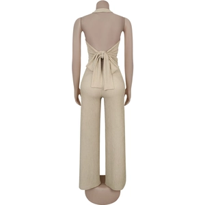 Detail view of the back of a beige halter neck jumpsuit featuring a large stylish bow tie
