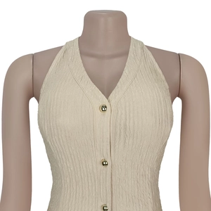 Close-up of pleated beige halter top featuring deep V-neck and three golden buttons