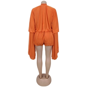 Detail view of the back of the orange pleated romper with flared sleeves and high neck
