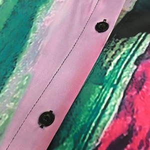 Dettaglio macro della camicia stampata astratta con bottoni neri e cuciture precise