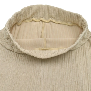 Detail view of the elastic waistband and pleated fabric texture on beige trousers